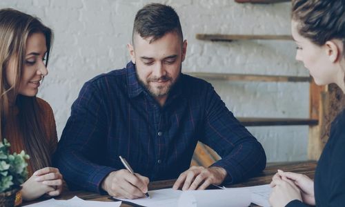 Couple signing paperwork at client meeting