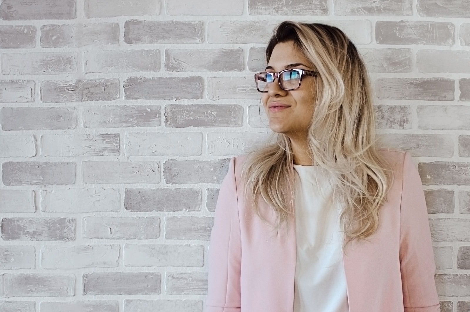 Woman in pink cardigan and white shirt leaning on the wall