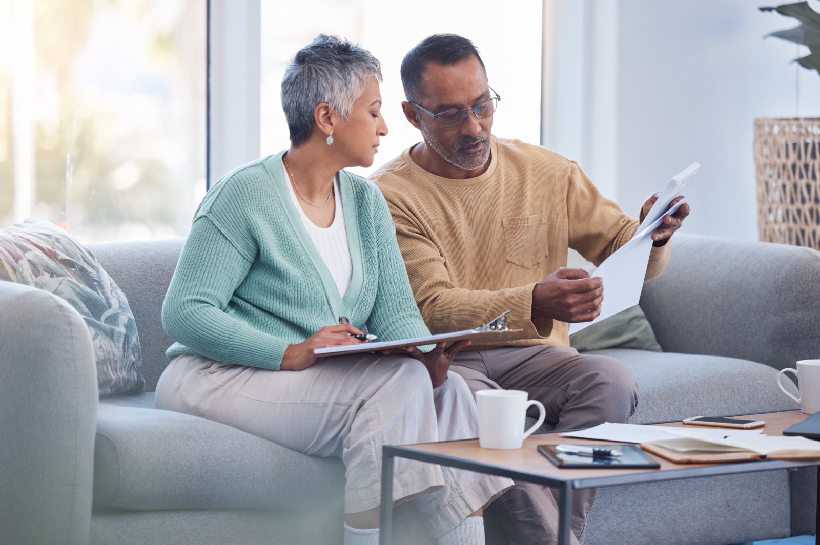 An older couple reviewing paperwork together on a sofa.