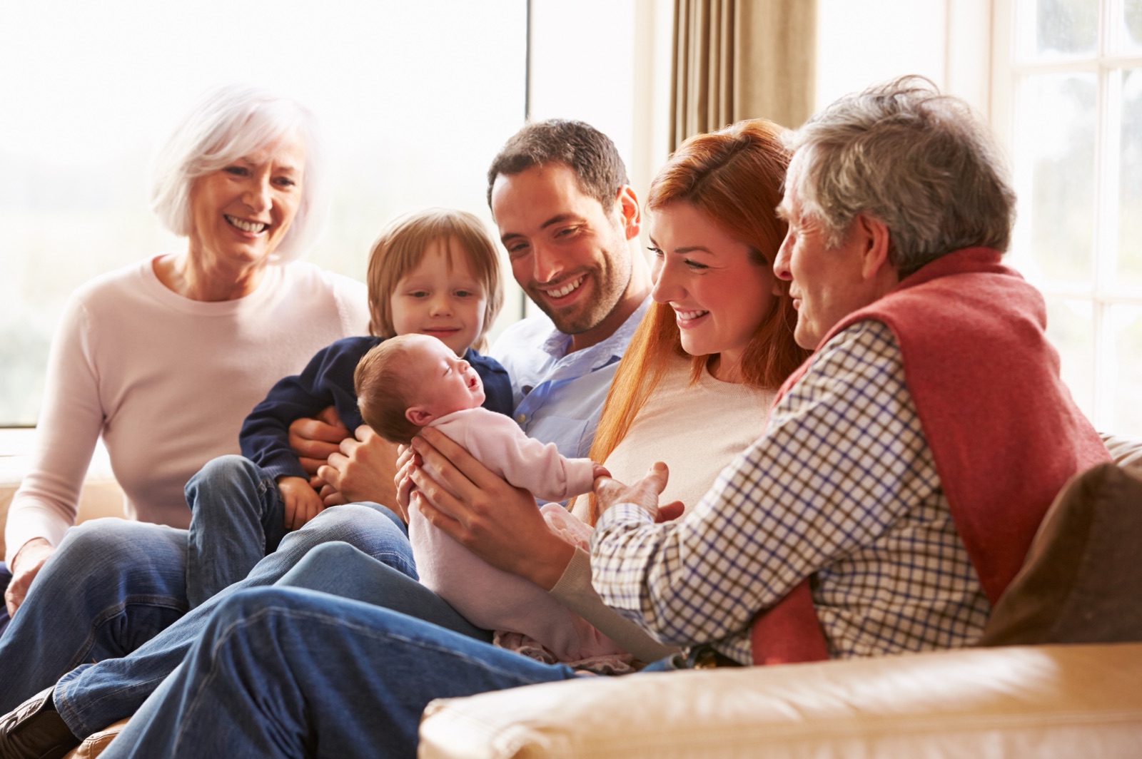A family gathered on a sofa around a newborn baby.