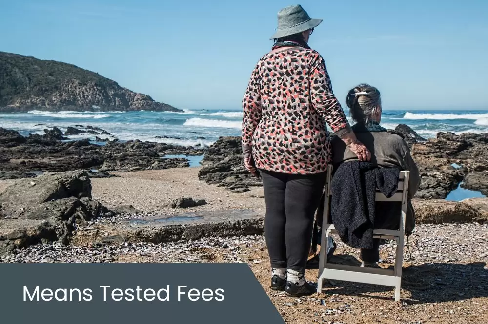 Means Tested Fees Elderly person with adult child sitting on beach